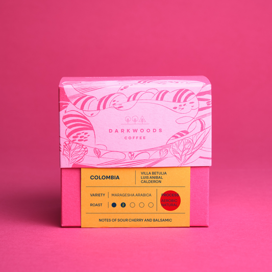 A packaged coffee product with iillustrated design on the upper half and a yellow label with text on the lower half, indicating the variety as 'Colombia Villa Betulia Ombligon' and the roast as 'Light'.